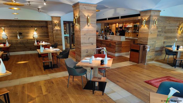 El interior con paneles de madera del restaurante Luce d'Oro, que incluye mesas, sillas y mesas más pequeñas para bolsos
