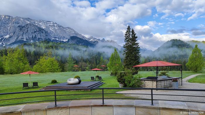 Vue depuis une terrasse du château d'Elmau sur le pré et les montagnes dans le brouillard du matin