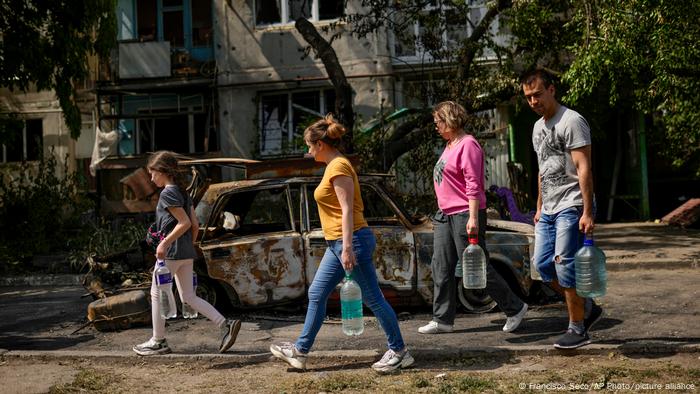 Moradores de Kharkiv, na Ucrânia, passam na frente de um prédio destruído