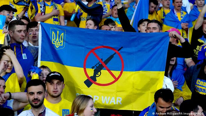 En un desempate clasificatorio para la Copa Mundial, en Escocia, aficionados del fútbol ucranianos muestran una bandera de su país con un mensaje contra la guerra.