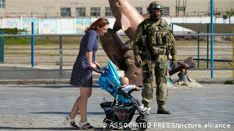 Женщина с коляской и российский военнослужащий в Херсоне