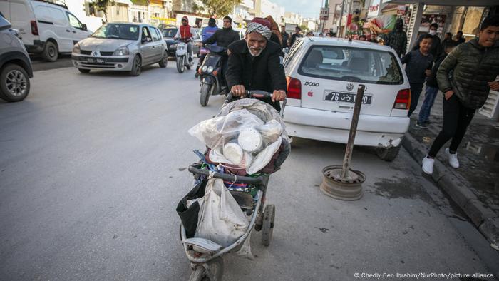 Ein älterer Mann schiebt einen Karren die Straße eines schwierigen Viertels in der beliebten Stadt Ettadhamen entlang, die eine der bevölkerungsreichsten Städte der Hauptstadt Tunis ist.