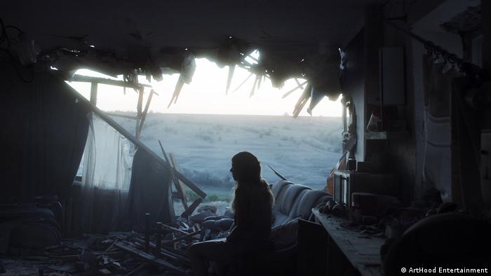Still from the film 'Klondike': a silhouette of a person in a house with a bombed out wall.