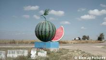 A film still from 'Volcano': A giant sculpture of a watermelon alongside a deserted road.