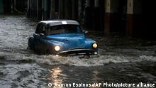 A person drives a classic American car through a street flooded by heavy rains, in Havana, Cuba, Friday, June 3, 2022. Heavy rains have drenched Cuba with almost non-stop rain for the last 24 hours as tropical storm watches were posted Thursday for Florida, Cuba and the Bahamas as the system that battered Mexico moves to the east. (AP Photo/Ramon Espinosa)