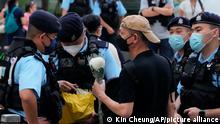 Police officers stop and search a man holding a flower at the Hong Kong's Victoria Park, Saturday, June 4, 2022. Dozens of police officers patrolled Hong Kong's Victoria Park on Saturday after authorities for a second consecutive third banned public commemoration of the anniversary of the Tiananmen Square crackdown in 1989, amid a crackdown on dissent in the city. (AP Photo/Kin Cheung)