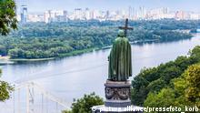 Drei Sehenswürdigkeiten auf einen Blick: Im Vordergrund das Denkmal für Wladimir den Heiligen (er hält ein Kreuz in der Hand), unten links die Parkovy-Brücke und dahinter der Fluss Dnepr.