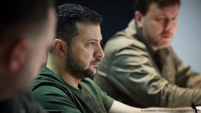 Ukrainian President Volodymyr Zelensky listening during a meeting, in a khaki T-shirt