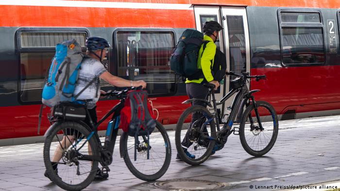 Reisende mit Fahrrädern und Rucksäcken steigen in einen Zug ein