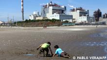 (FILES) In this file photo taken on October 8, 2019 children play in the sand at Las Ventanas beach next to the AES Gener thermoelectric plant in Puchuncavi, Valparaiso region, Chile. - At least 75 people, including some 50 school children, were intoxicated due to the high levels of pollution in the heavy industry areas of Quintero and Puchuncavi, considered zones of environmental sacrifice, informed authorities on June 7, 2022. (Photo by Pablo VERA / AFP)