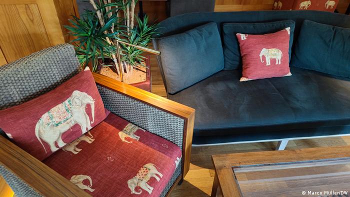 A chair with elephant fabric and a pillow with elephant fabric on a sofa.