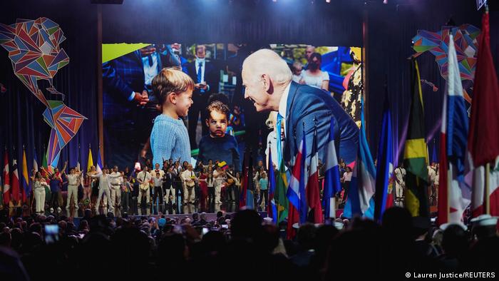 Participants at the Summit of the Americas, wide shot showing a full main stage and an image of Joe Biden on a big screen.
