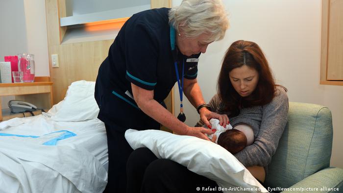A nurse helps a woman to breastfeed in the hospital