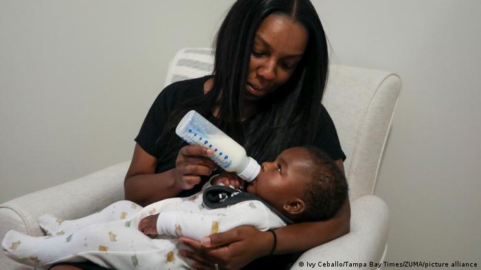 Eine Mutter gibt ihrem Sohn Milch aus einem Fläschchen
