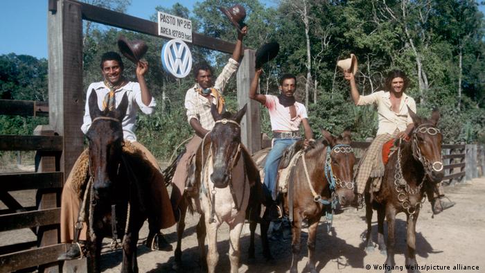 Four men on horseback holding cowboy hats