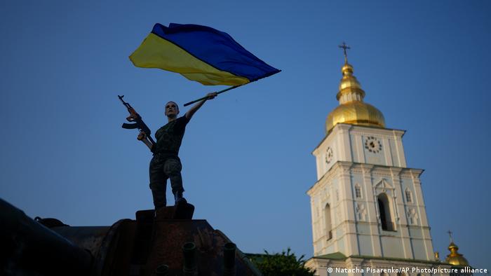view of Kyiv church, silhouette of fighter with gun and Ukrainian flag
