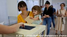 A girl casts the ballot for her mother at a voting station in Strasbourg, eastern France, Sunday June 12, 2022, Sunday, June 12, 2022. French voters are choosing lawmakers in a parliamentary election as President Emmanuel Macron seeks to secure his majority while under growing threat from a leftist coalition. (AP Photo/Jean-Francois Badias)