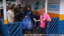 Federal police officers arrive at the pier with items found during a search for Indigenous expert Bruno Pereira and freelance British journalist Dom Phillips in Atalaia do Norte, Amazonas state, Brazil, Sunday, June 12, 2022. Divers from Brazil's firefighters corps found a backpack and laptop Sunday in the remote Amazon area where Pereira and Phillips went missing a week ago, firefighters said. (AP Photo/Edmar Barros)