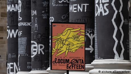 A poster for documenta fifteen is seen outside a museum with black-and-white painted columns