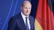 German Chancellor Olaf Scholz speaks in front of a German flag German Chancellor Olaf Scholz speaks in front of a German flag