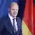 German Chancellor Olaf Scholz speaks in front of a German flag