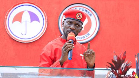 Robert Seentamu Kyagulanyi alias Bobi Wine, man with a red hat speaks into a microphone 