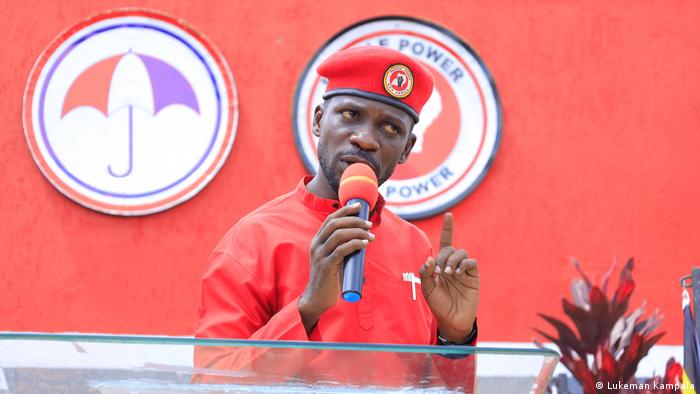 Robert Seentamu Kyagulanyi alias Bobi Wine hält eine politische Rede. Er trägt eine rote Baskenmütze. 