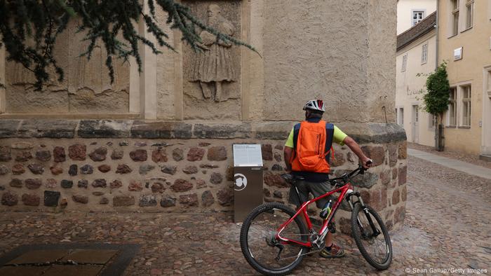 Ein Radfahrer betrachtet eine Informationstafel an der Stadtkirche Wittenberg