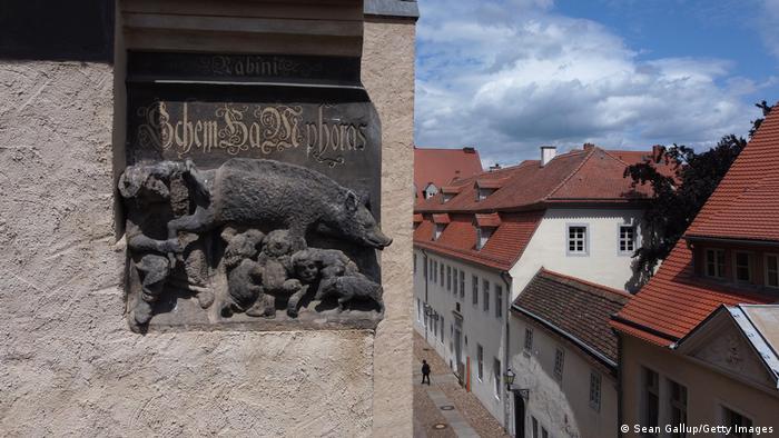 Ein Relief an der Stadtkirche Wittenberg zeigt Menschen mit spitzen Hüten, die von einem Schwein gesäugt werden