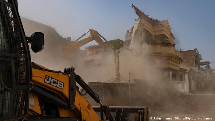 A bulldozer knocks down a house