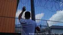 A protester communicates with those inside at the perimeter fence of Brook House immigration removal centre beside Gatwick Airport, south of London on June 12, 2022, as demonstrators gather to protest against the UK government's intention to deport asylum-seekers to Rwanda. - UK campaigners get their last chance in court on Monday to stop the government's first flight of asylum-seekers to Rwanda. The government is vowing to push ahead with the first planeload of 31 claimants, on a chartered flight Tuesday from an undisclosed airport in Britain. (Photo by Niklas HALLE'N / AFP) (Photo by NIKLAS HALLE'N/AFP via Getty Images)