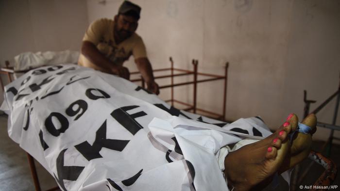 An employee covers the body of a transgender victim, who was attacked by unknown gunmen, at a morgue in Karachi
