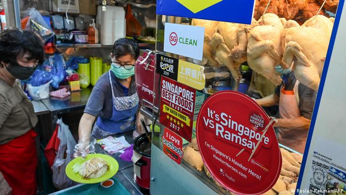 Seorang penjual menyiapkan sepiring nasi ayam di pusat jajanan di Singapura