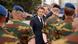French President Macron surrounded by soldiers wearing camouflage and blue caps 