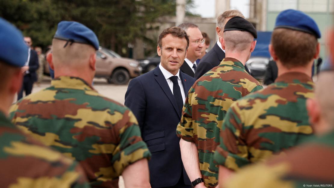 French President Macron surrounded by soldiers wearing camouflage and blue caps 