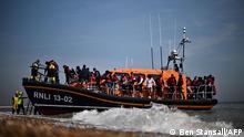 TOPSHOT - Migrants, picked up at sea attempting to cross the English Channel, are helped ashore from an Royal National Lifeboat Institution's (RNLI) lifeboat at Dungeness on the southeast coast of England, on June 15, 2022. - Furious Conservatives called on Britain's government on June 15, 2022 to abandon a European human rights pact after a judge dramatically blocked its plan to fly asylum-seekers to Rwanda. Under the UK's agreement with Rwanda, all migrants arriving illegally in Britain are liable to be sent to the East African nation thousands of miles away for processing and settlement. The government, after arguing that Brexit would lead to tighter borders, says the plan is needed to deter record numbers of migrants from making the perilous Channel crossing from northern France. (Photo by Ben Stansall / AFP)