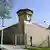 Das ehemalige Stasi-Gefängnis in Berlin-Hohenschönhausen: hohe Mauern, ein Wachturm, Stacheldraht und Scheinwerfer 