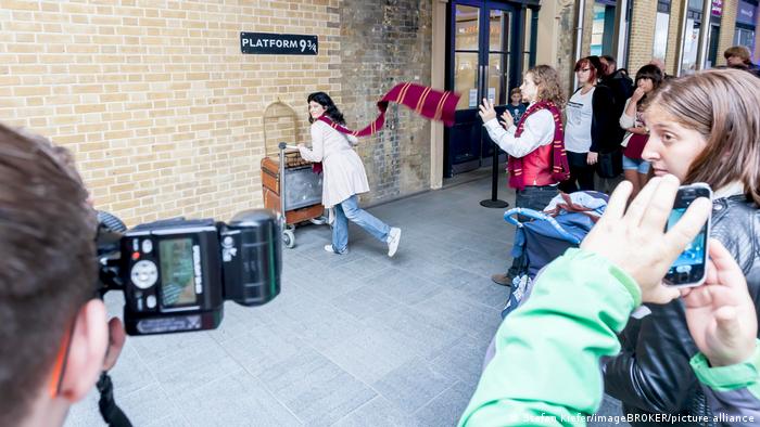 Touristen fotografieren den Bahnsteig 9 3/4 am Londoner Bahnhof King's Cross Station