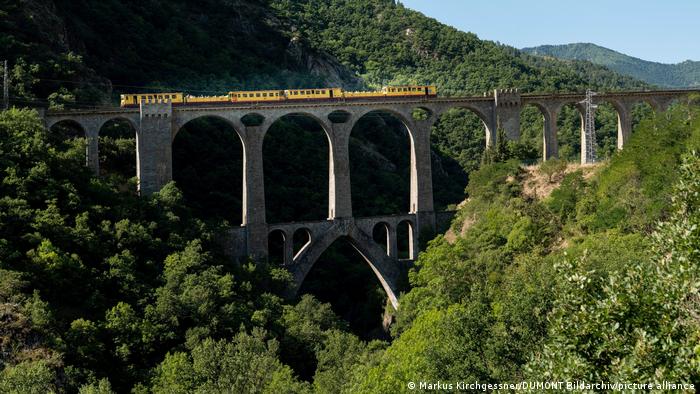 A yellow train passes the Sejourne Viaduct