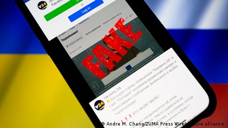 A smartphone displaying the Ukraine 24 facebook with the word fake imposed on top