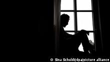 Un hombre sentado junto a una ventana, en sombras.
