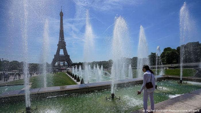Una mujer se refresca en la fuente del jardín Trocadero junto a la torre Eiffel, en París, Francia (16.06.2022)