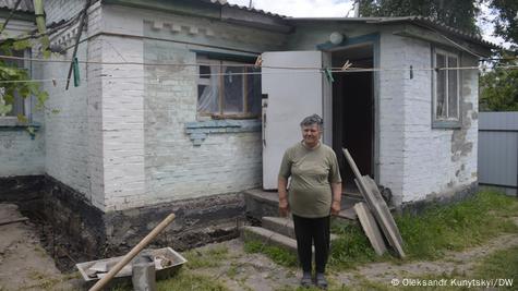 Жительница села Микуличи у своего дома