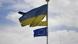 A tattered Ukrainian flag flies next to an EU flag against a partly cloudy sky A tattered Ukrainian flag flies next to an EU flag against a partly cloudy sky