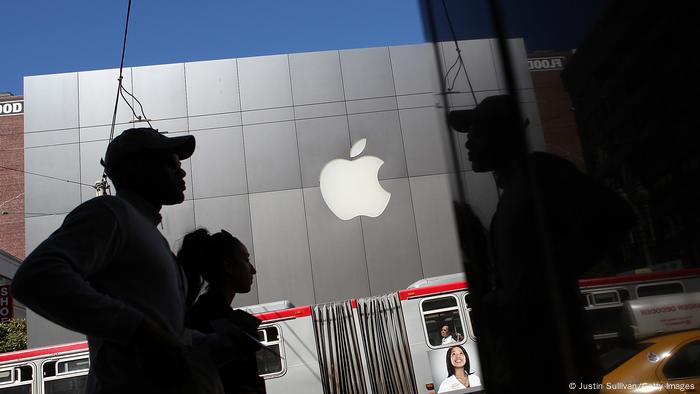 Two people in the backlight in front of the Apple logo