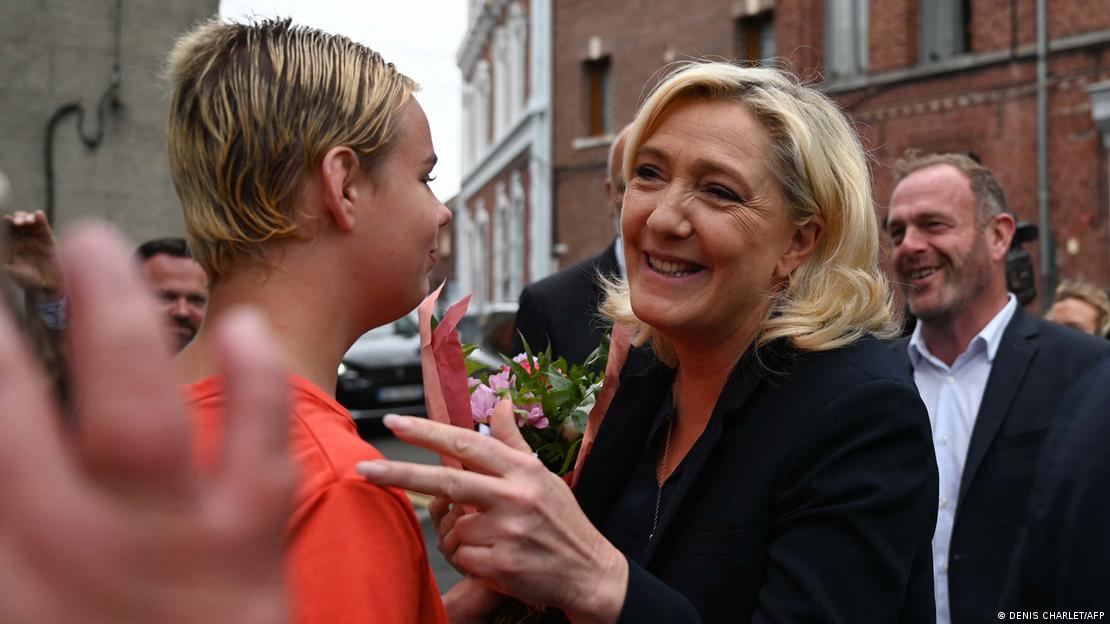 French far-right party Rassemblement National (RN) leader Marine Le Pen speaks with a woman after casting her vote in the second stage of French parliamentary elections at a polling station at Henin-Beaumont, northern France on June 19, 2022.