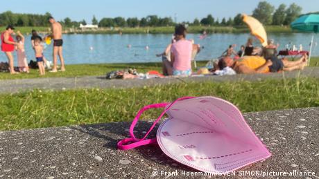 Защитная маска на фоне отдыхающих на берегу озера немцев 