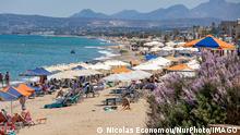 Tourism In Greece - Beach Life Of Rethymno Coast In Crete Island Tourism in Greece. The coast of Rethymno town with the long sandy beach and the beach bars in Creta island with the mountains in the background. People are seen tanning while wearing bathing suit, swimsuit, bikini, enjoying the sun under the umbrella at the beach bar on a sun bed, and swimming in the crystal clear sea. Rethymno is a historic Mediterranean beach town on the northern coast of Crete, laying on the Aegean Sea with a population of 40.000 people. A touristic destination with a historic Venetian port and town, archaeological sites, endless sandy beaches, watersports, nice beautiful traditional taverns, and a big variety of hotels. Tourism is bouncing back with reserv PUBLICATIONxNOTxINxFRA Copyright: xNicolasxEconomoux originalFilename: economou-tourismi220613_np1sU.jpg