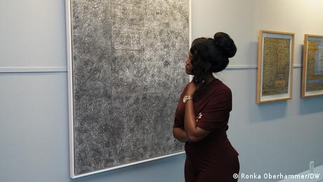 Woman looks at a large painting on a white wall