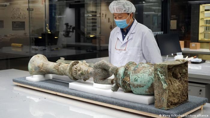 Lei Yu, investigador del Instituto Provincial de Investigación de Reliquias Culturales y Arqueología de Sichuan, observa una escultura de bronce que ha sido emparejada con éxito y que representa una figura con cabeza humana, cuerpo de serpiente y garra de pájaro.